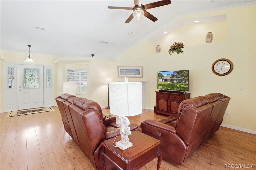 2593 S Columbine Avenue, Homosassa, FL 34448 Living Room Spacious living area with vaulted ceiling, crown molding, wood-look flooring, ceiling fan & open layout.