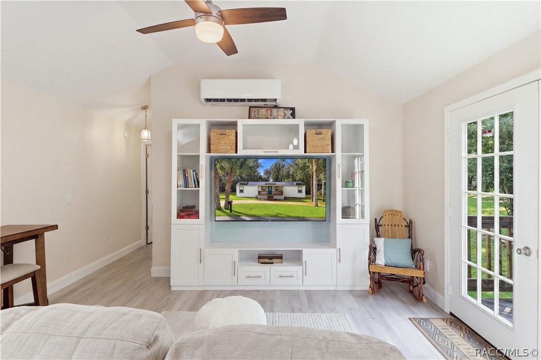 6230 W Glen Robbin Court, Crystal River, FL 34429 Living Room Bright & inviting living room featuring VAULTED CEILINGS, luxury vinyl plank flooring, ceiling fan, w/entertainment cabinetry & a MINI-SPLIT HEATING & COOLING SYSTEM. French doors provide views of the backyard & access to the rear deck.