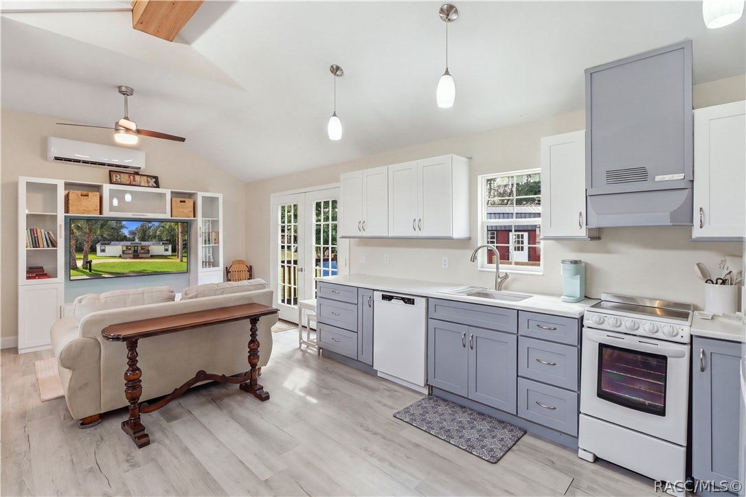 6230 W Glen Robbin Court, Crystal River, FL 34429 Kitchen & French Doors Bright kitchen featuring white upper cabinetry, soft blue-gray lower cabinetry, SOLID SURFACE COUNTERTOPS & French doors leading to the outdoor deck.