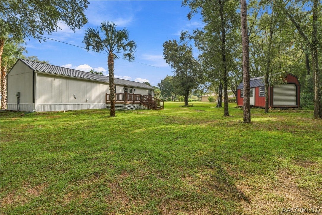 6230 W Glen Robbin Court, Crystal River, FL 34429 Backyard & Storage Building Spacious backyard featuring mature trees, open lawn, wooden deck & a distinctive RED DETACHED STORAGE BUILDING w/metal roof & roll-up door.