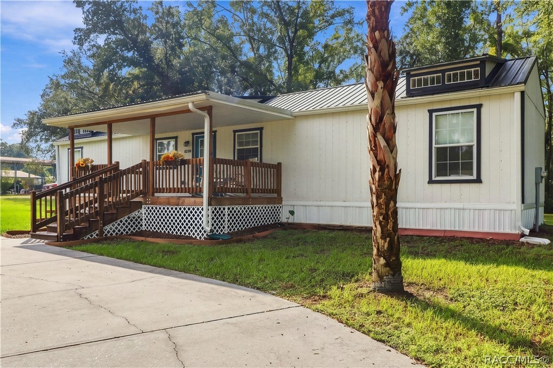 6230 W Glen Robbin Court, Crystal River, FL 34429 Exterior & Front Porch Another inviting perspective highlighting the covered wooden porch, contrasting exterior finishes & beautiful palm tree.