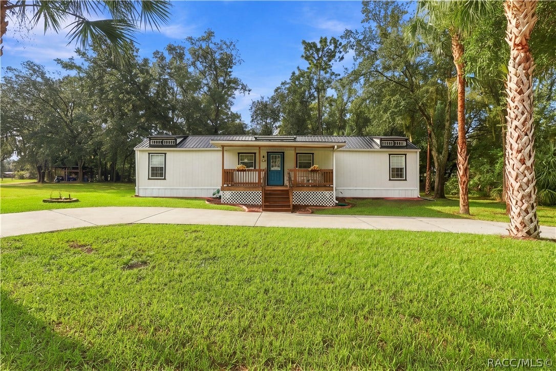 6230 W Glen Robbin Court, Crystal River, FL 34429 Charming Front Exterior Beautifully presented home featuring a METAL ROOF, inviting COVERED FRONT PORCH, attractive landscaping & a welcoming blue front door.