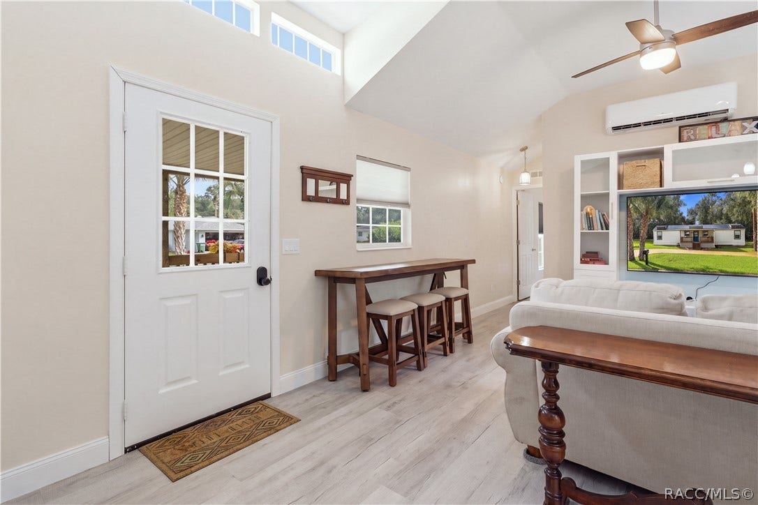 6230 W Glen Robbin Court, Crystal River, FL 34429 Living Area & Front Entry Welcoming living space featuring VAULTED CEILINGS, high transom windows, ceiling fan, attractive flooring & a convenient seating area near the front entrance.