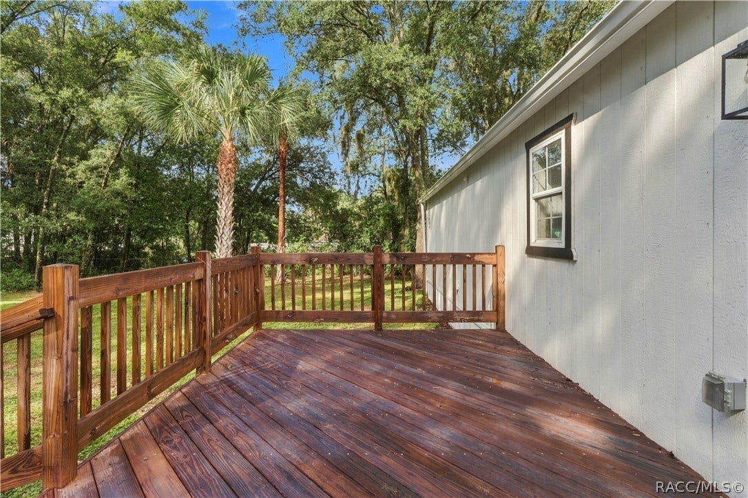 6230 W Glen Robbin Court, Crystal River, FL 34429 Rear Deck Spacious wooden deck featuring sturdy railings & room for outdoor seating, surrounded by Florida greenery & mature palms.