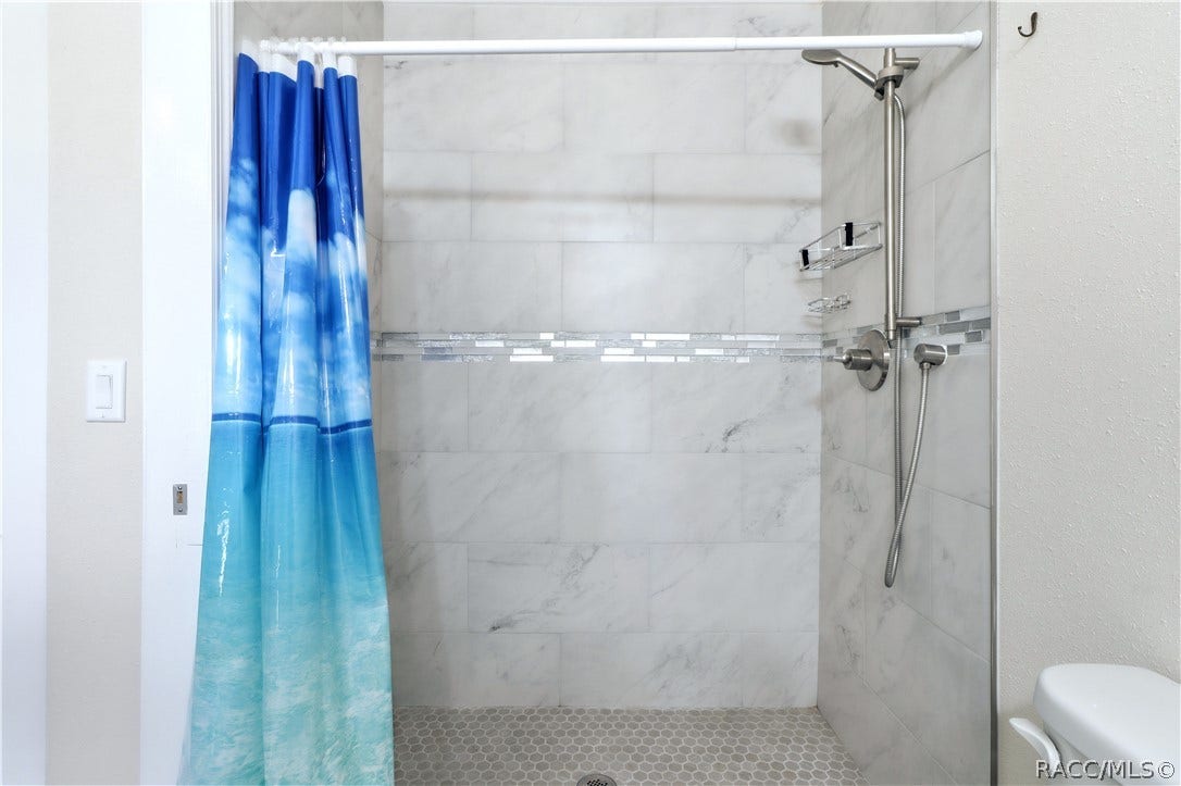 6230 W Glen Robbin Court, Crystal River, FL 34429 Primary Bathroom Shower Beautifully tiled WALK-IN SHOWER featuring marble-look wall tile, decorative mosaic accent & handheld showerhead.