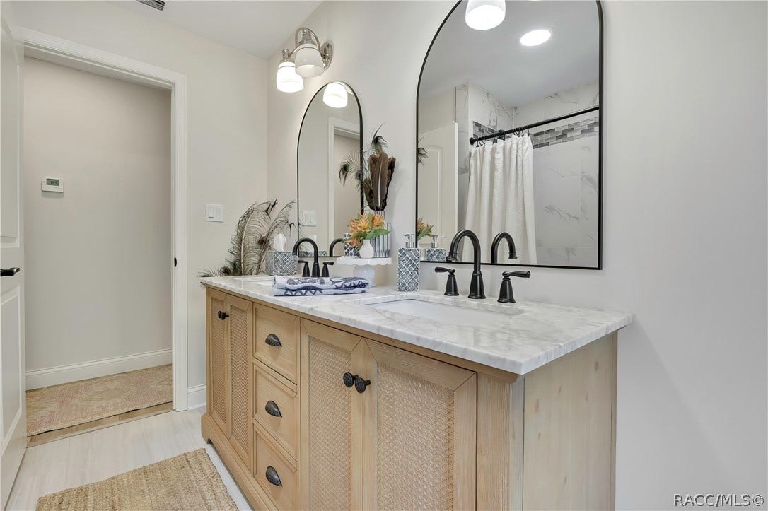 11806 W Riverhaven Drive, Homosassa, FL 34448 Double vanity with arched mirrors and light wood cabinets.