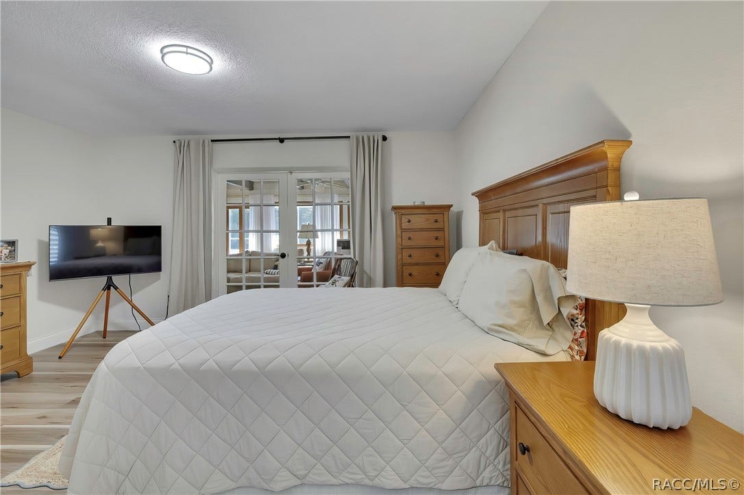 11806 W Riverhaven Drive, Homosassa, FL 34448 Bedroom with bedside lamp and sliding doors beyond