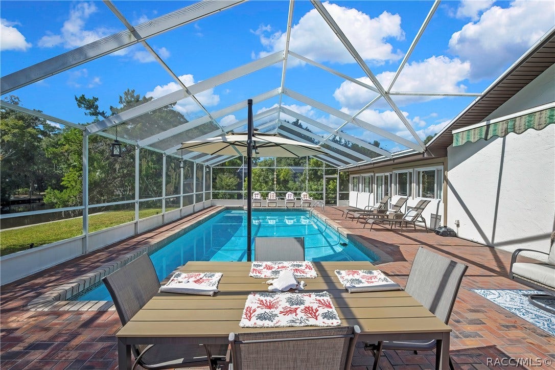 11806 W Riverhaven Drive, Homosassa, FL 34448 Screen-enclosed pool with patio dining set.
