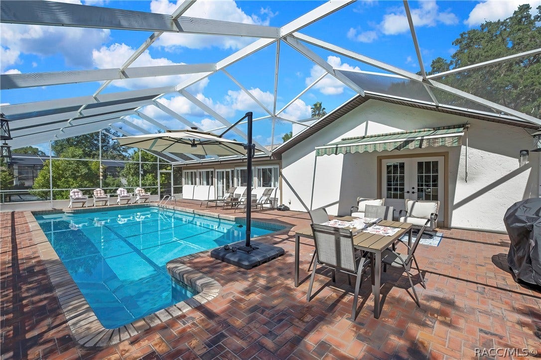 11806 W Riverhaven Drive, Homosassa, FL 34448 Pool deck with outdoor dining beside the home.