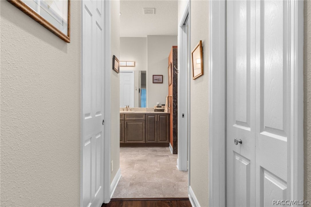 The primary suite hallway leading to the ensuite bath is flanked by walk-in closets on either side.