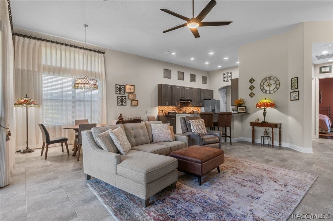 View of the greatroom and kitchen upon exiting the primary suite. On the right of this picture is a glimpse down the guest hall to the guest bedroom.