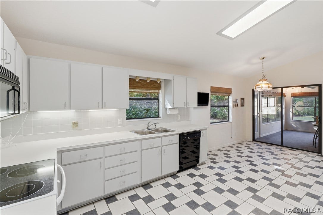 A KITCHEN WITH ROOM TO MOVE! Generous countertop space, abundant cabinetry, DOUBLE-BASIN SINK & convenient access to the ENCLOSED FLORIDA ROOM!