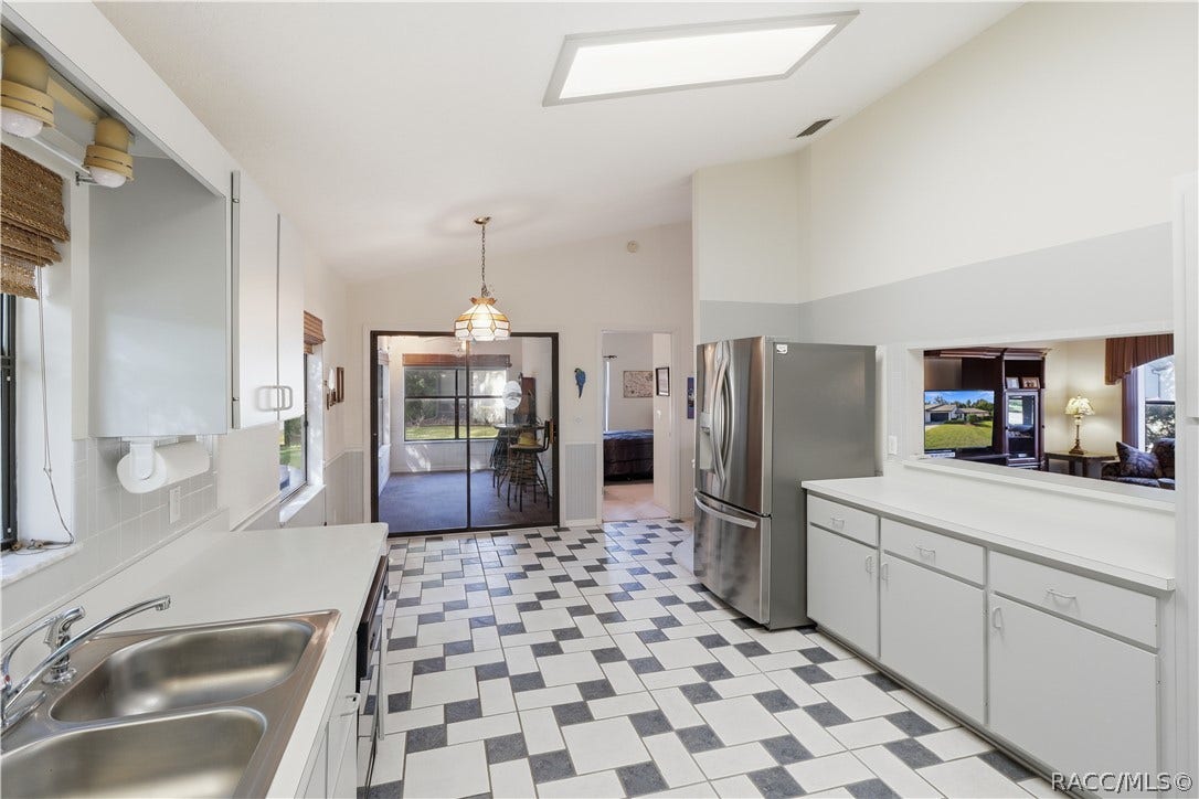 THE HEART OF THE HOME! Functional kitchen layout offers GRAY CABINETRY, STAINLESS STEEL REFRIGERATOR, PASS-THROUGH TO LIVING ROOM & convenient access to adjoining spaces!