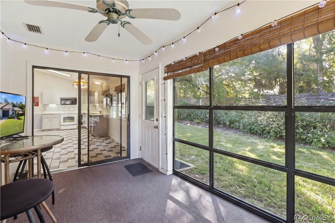 Enclosed rear porch with expansive screened windows, ceiling fan, and views of the landscaped backyard.