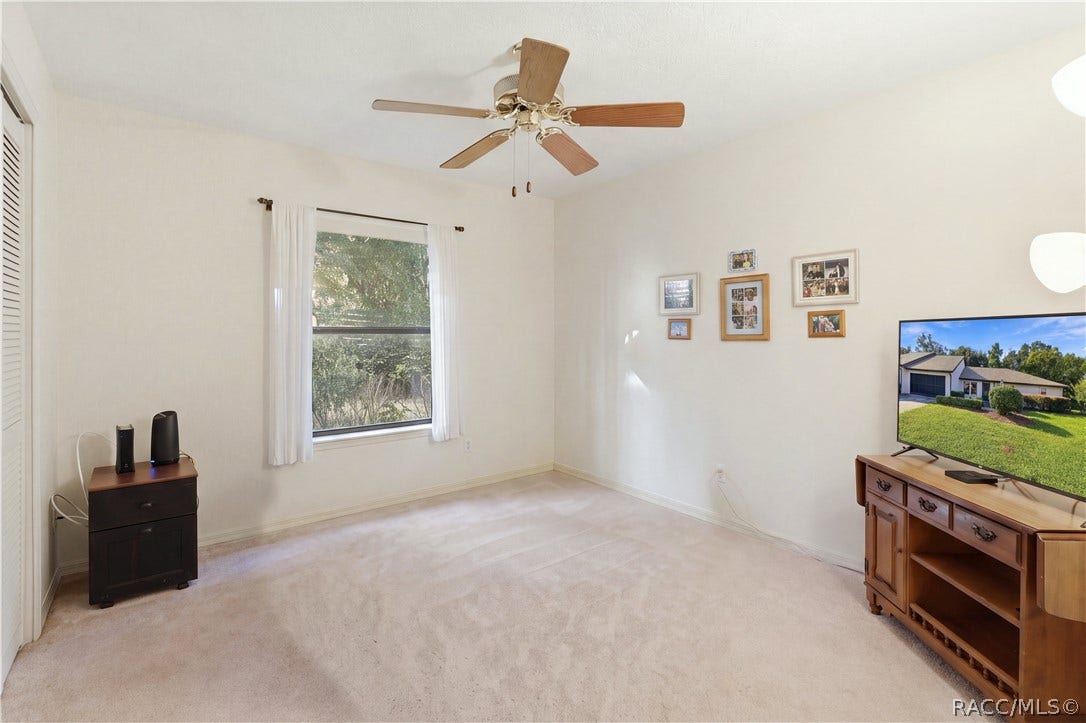 Additional view of the guest bedroom showcasing natural light, ceiling fan, carpeting.
