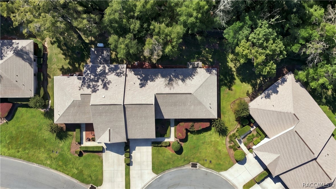 Overhead aerial view showcasing the home's layout, driveway, surrounding greenery, and neighboring residences