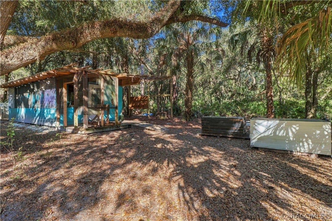 7528 N Chabaud Terrace, Crystal River, FL 34428 COUNTRY CHARACTER & OUTDOOR POSSIBILITIES! This rustic outbuilding features a covered wooden porch & adjoining open-air structure beneath the shade of mature trees.