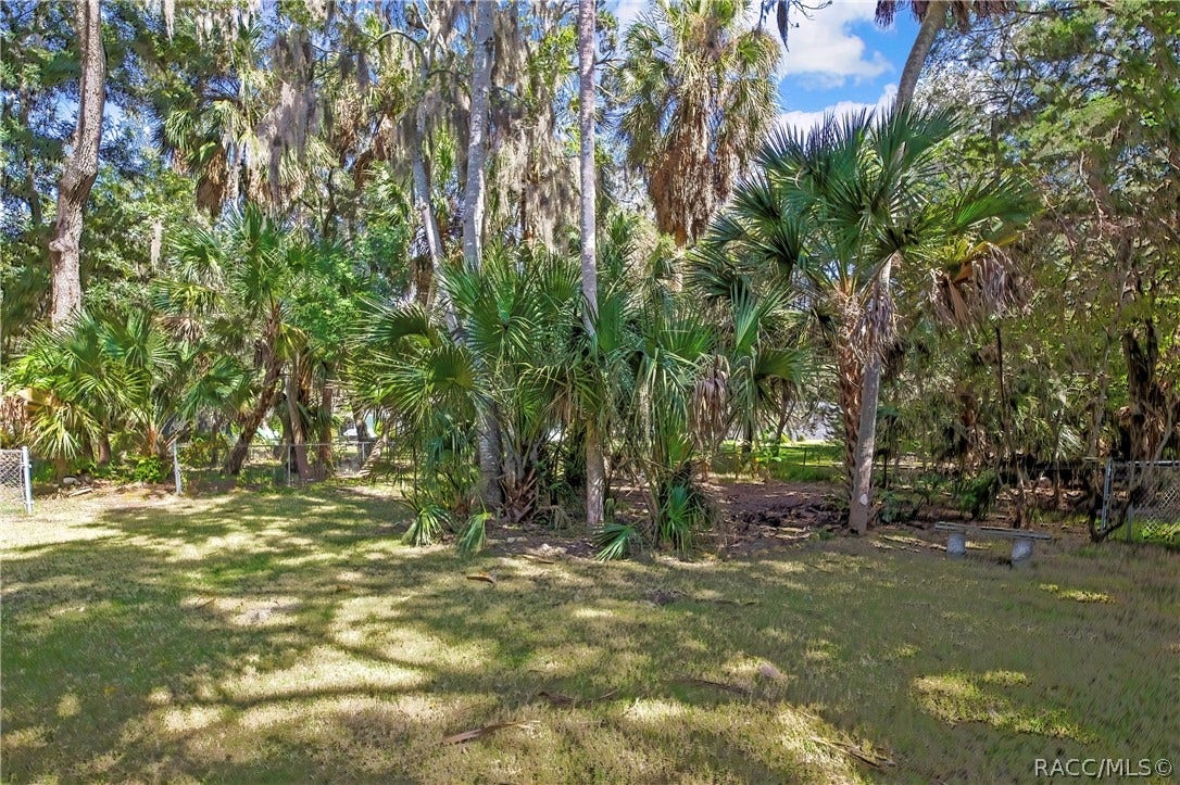 4737 S Sawmill Way, Homosassa, FL 34448 Bathroom: white vanity with a modern chrome faucet, a navy-and-white towel hanging over the vanity, a white toilet with a patterned container on the tank, a walk-in shower with stone-look tile walls, a mosaic accent strip, a grab bar and a pebble floor with a drain, recessed ceiling lights, and a 2-light fixture at the top left. This is the single-sink hall bath, not the primary bath.