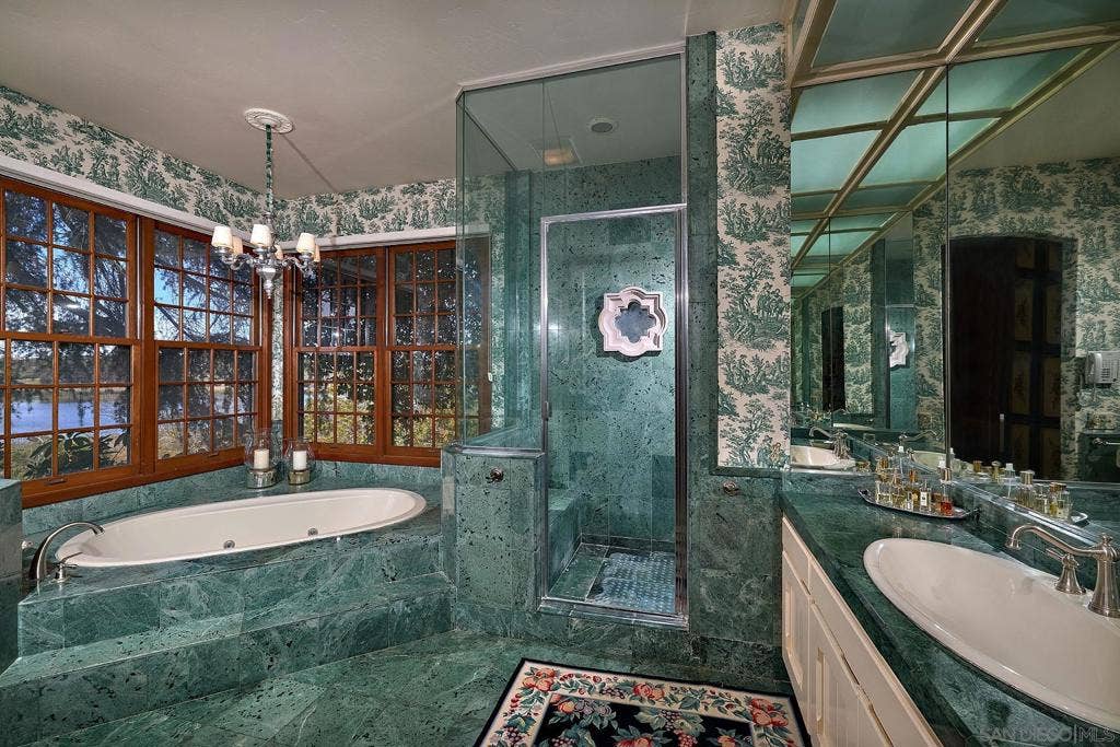 Ensuite are his and hers bathrooms and dressing rooms. The ladys bath has an oversized walk-in closet, a sumptuous bathroom and dressing area that features emerald green marble tiling, matching green pastoral toile wall coverings, and a free-standing tub