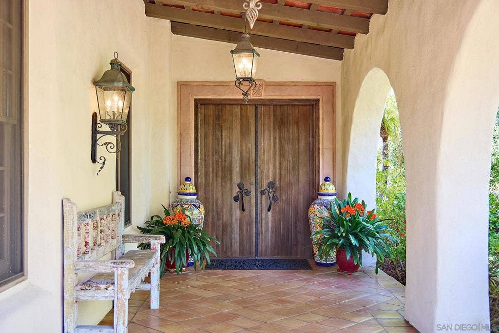 Beautiful custom front doors with detailed hardware.   Ivory stucco exterior, red clay tile roof, Moorish chimneys