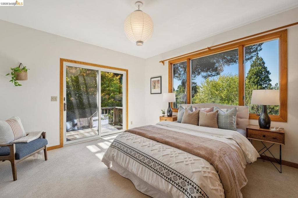 Wall-to-wall carpeting, large windows with natural wood trim, and a glass sliding door providing outdoor access