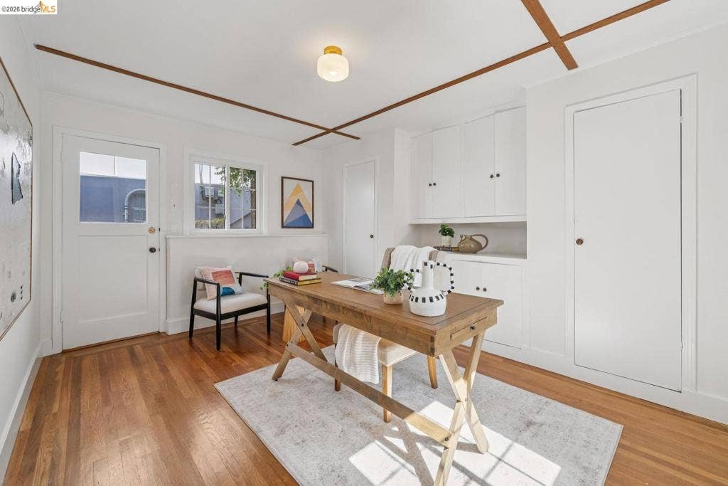 Hardwood flooring, built-in cabinetry, window with natural light, ceiling with wood-finish beams, and recessed lighting