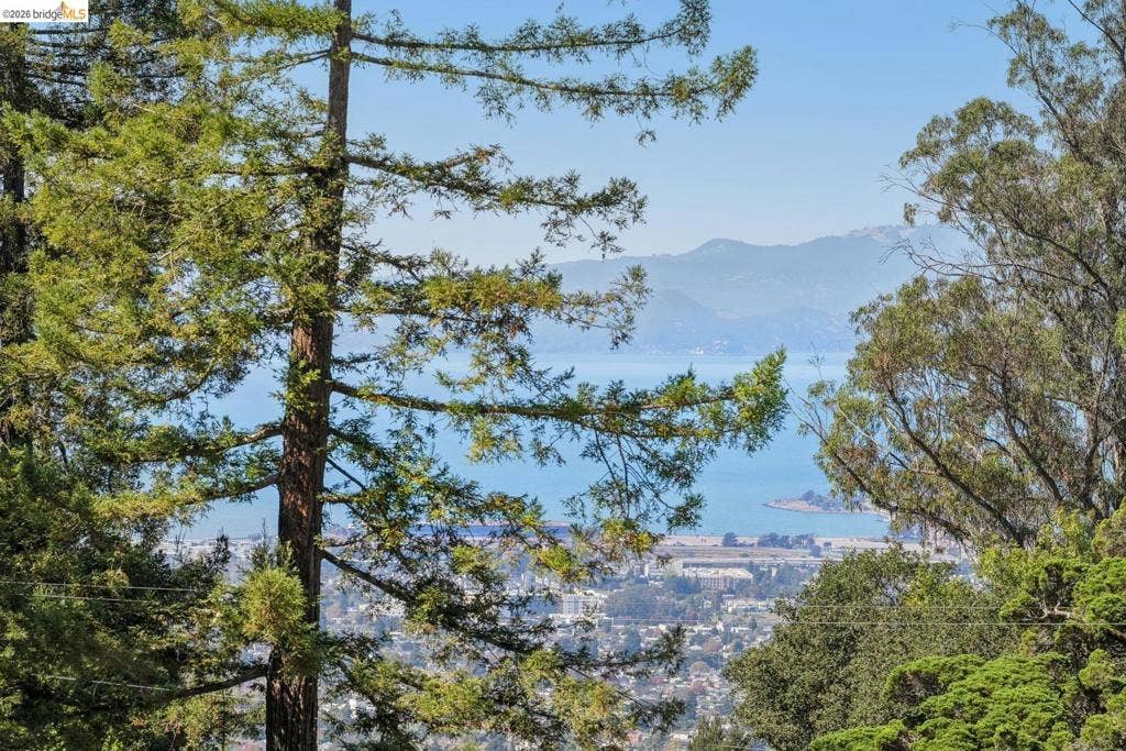 Expansive scenery featuring a broad body of water, distant mountains, and a city below