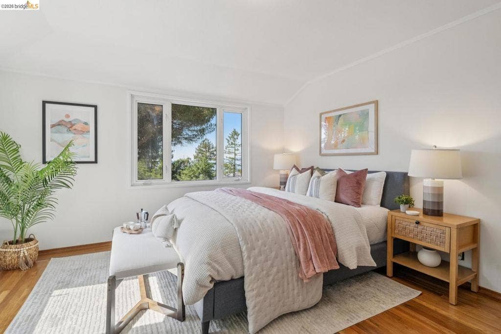 Hardwood flooring, white painted walls, white framed windows, and a sloped ceiling