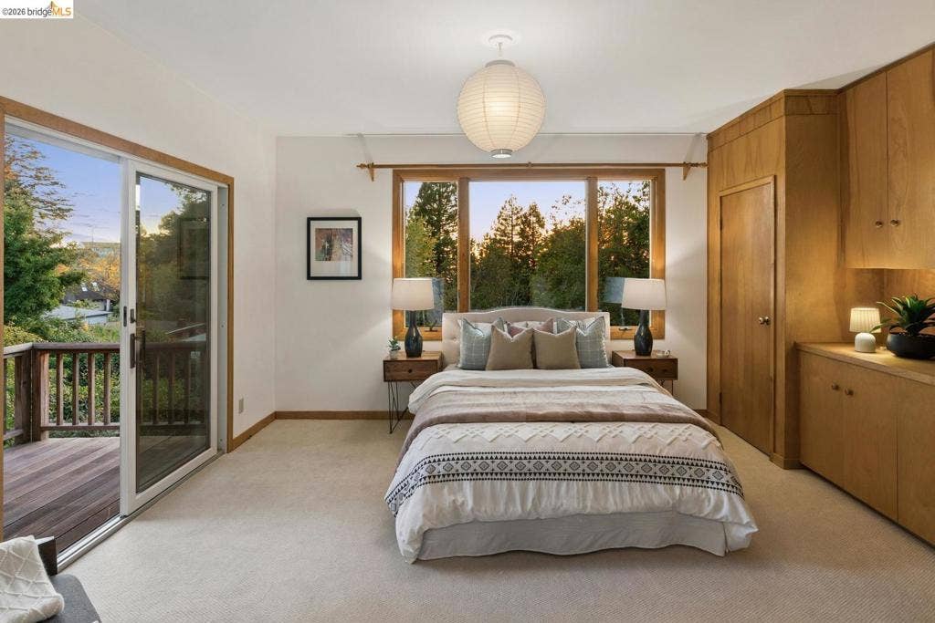 Built-in wooden cabinetry, a sliding glass door opening to a private deck, wood-framed windows, and carpeted flooring
