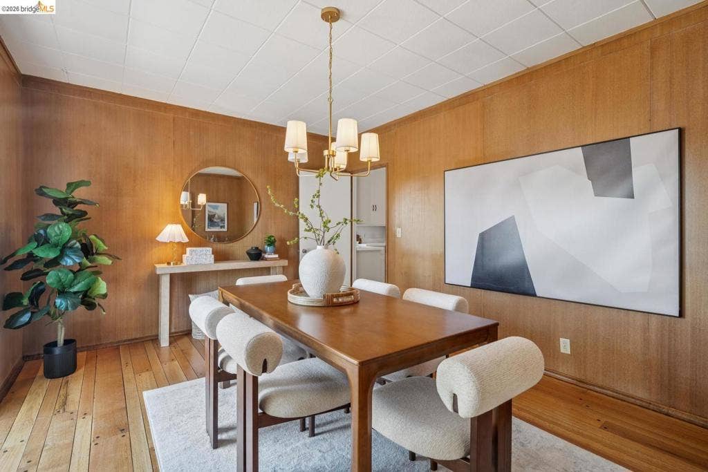 Warm wood paneling, polished wood-finish flooring, and a contemporary chandelier