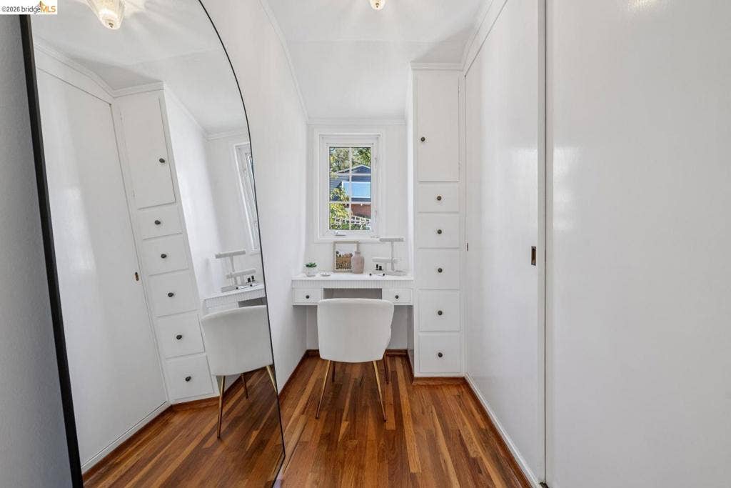 Built-in desk with window, integrated storage cabinetry with drawers, wood-finish flooring, and a flush-mount ceiling light fixture