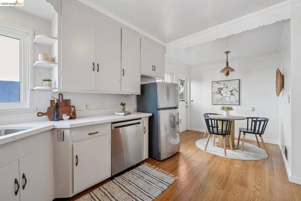 Kitchen featuring white cabinetry with dark hardware, a stainless steel dishwasher, and light-toned countertops
