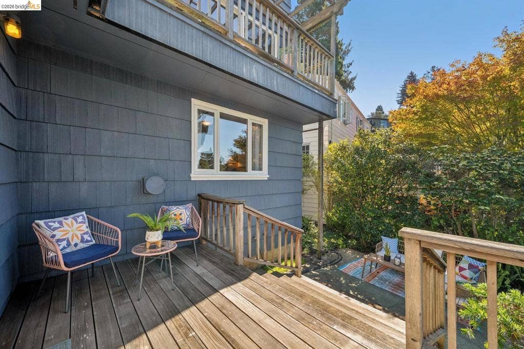 Deck with wood-finish flooring, featuring a shingle exterior, white-framed window, and wood railings