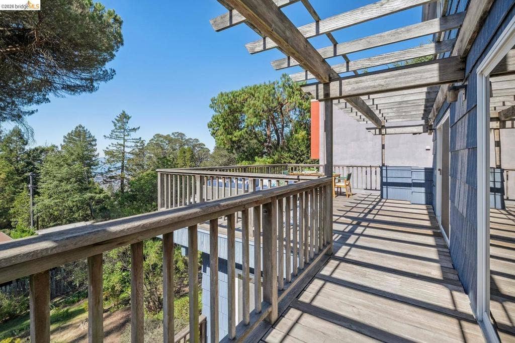 Expansive wood deck with a slatted wood pergola, wood railing, and blue siding