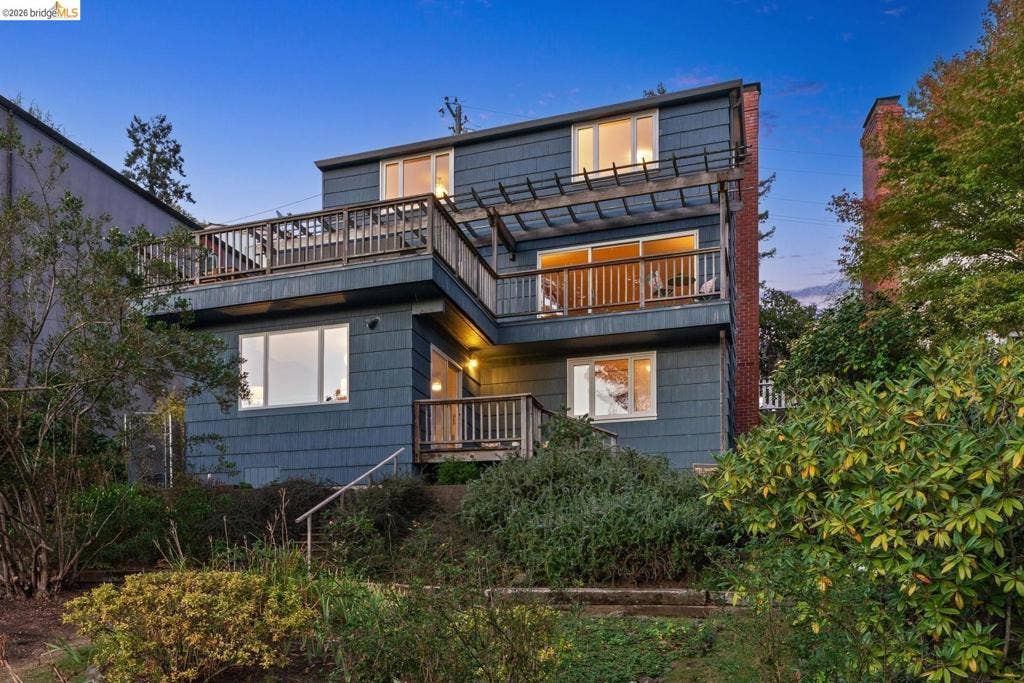 Multi-level exterior with shingle siding, multiple balconies, and a wooden pergola structure