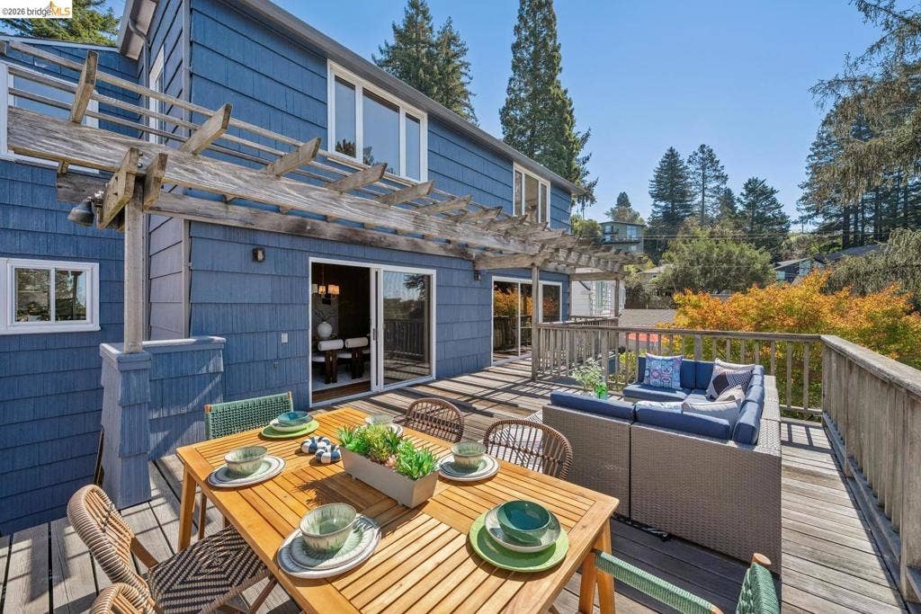 Expansive outdoor deck with a pergola, wooden railings, and multiple sliding glass doors providing access to the interior
