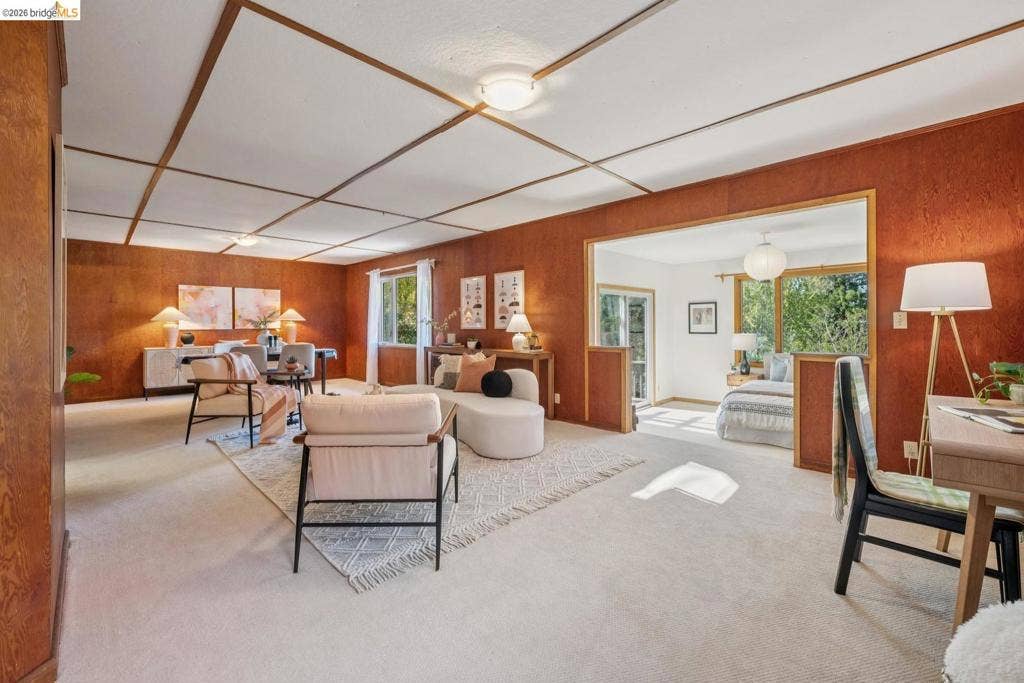 Wood paneling throughout, light-toned carpeting, wood-paneled ceiling with grid detailing, recessed lighting, and a broad cased opening