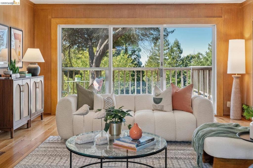 Wood paneling, expansive sliding glass doors, exterior balcony with railing, natural wood flooring, built-in storage cabinet