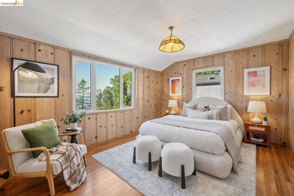 Wood paneling throughout, hardwood flooring, white window frames, and a textured white ceiling