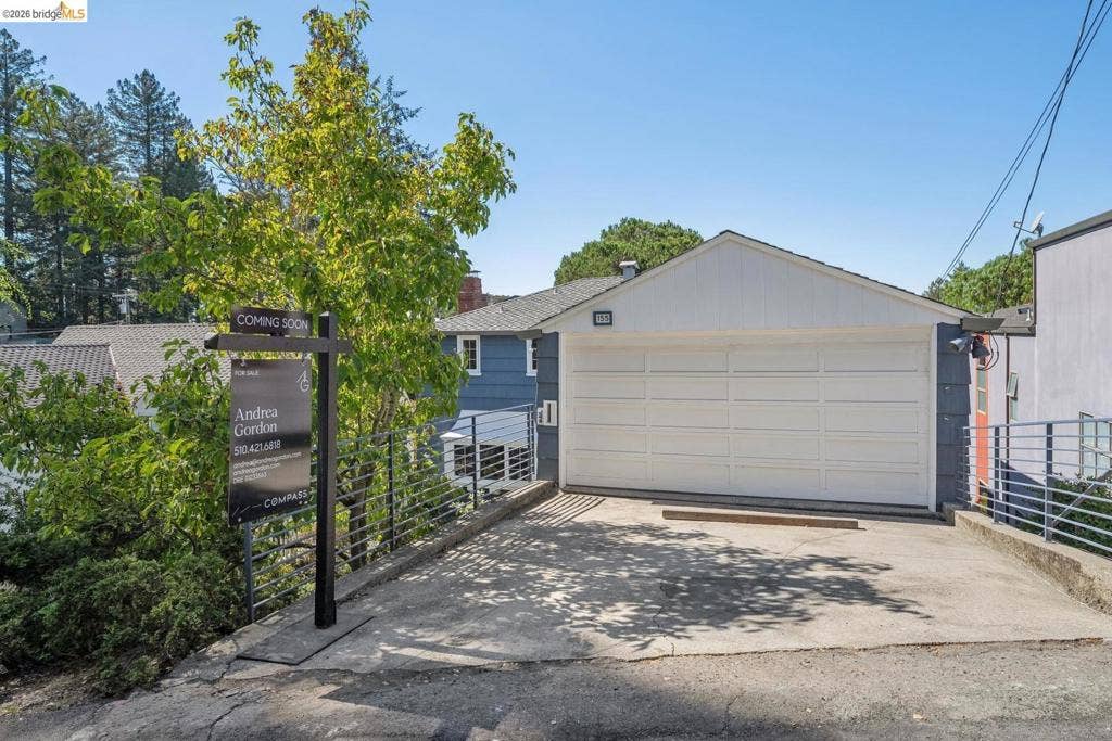 White panel garage door with a concrete driveway and metal railings