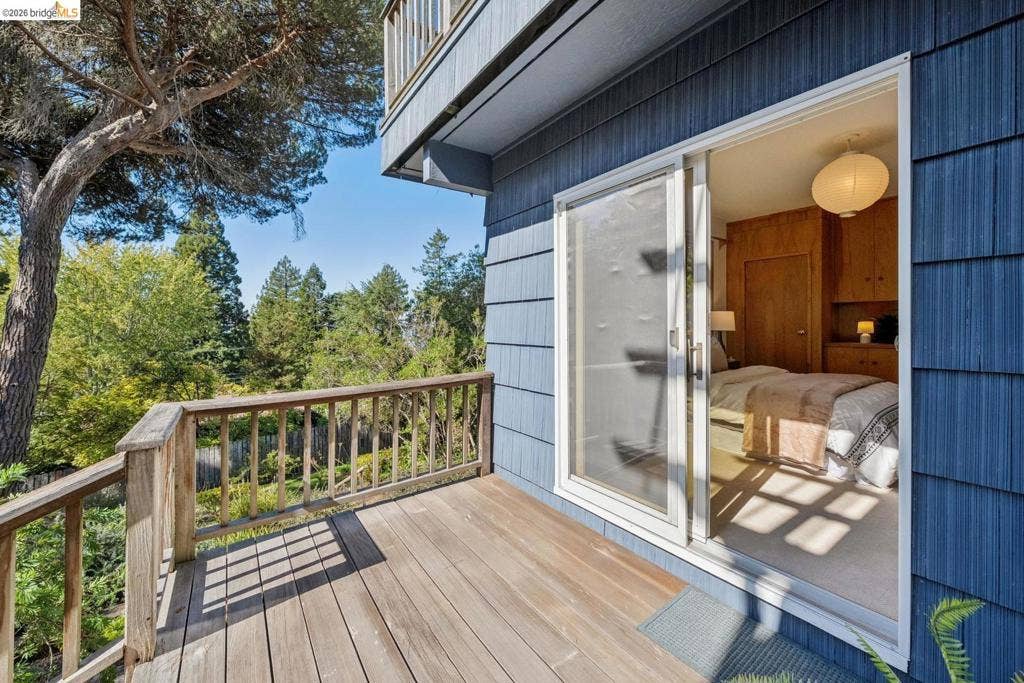 Exterior deck with wood railing, blue shingle siding, and sliding glass door