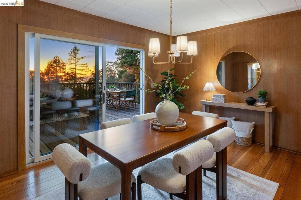 Wood-paneled room with wood-finish flooring, a sliding glass door, a wood-plank deck, and a multi-arm chandelier