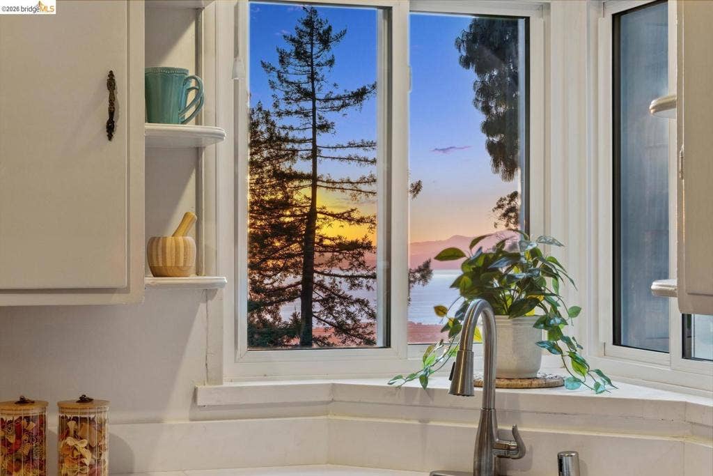 Corner window with a stainless steel faucet and white shaker-style cabinetry