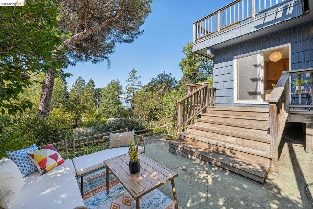 Expansive outdoor patio with concrete flooring, wood-plank stairs, and a multi-level deck