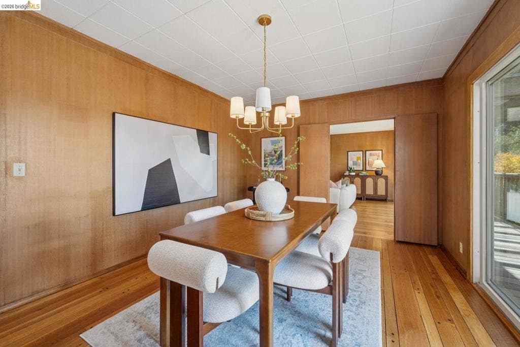 Wood-paneled walls, wood-finish flooring, and a multi-light chandelier