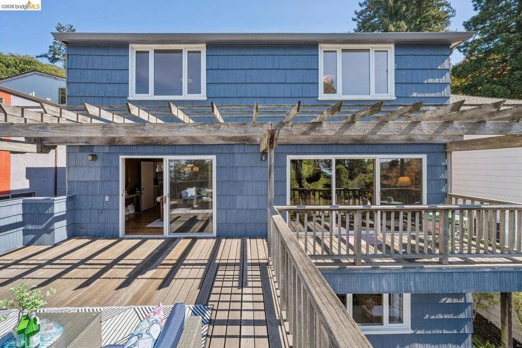 Multi-level decking with wood railing, pergola, and blue shingle siding