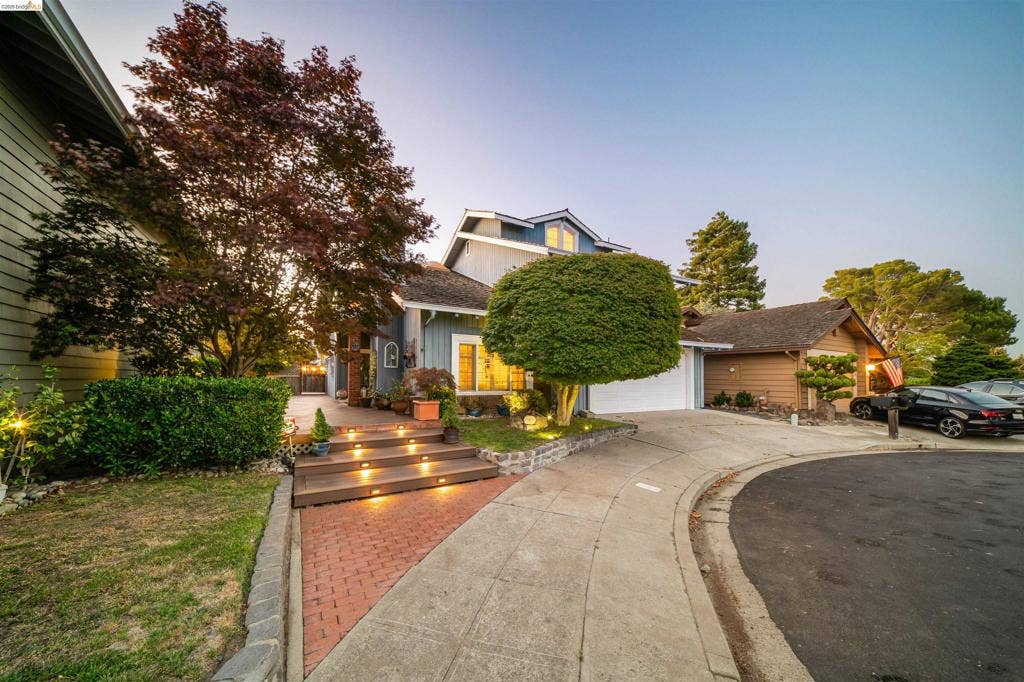 Split-level exterior with a multi-level deck, integrated step lighting, and an attached two-car garage