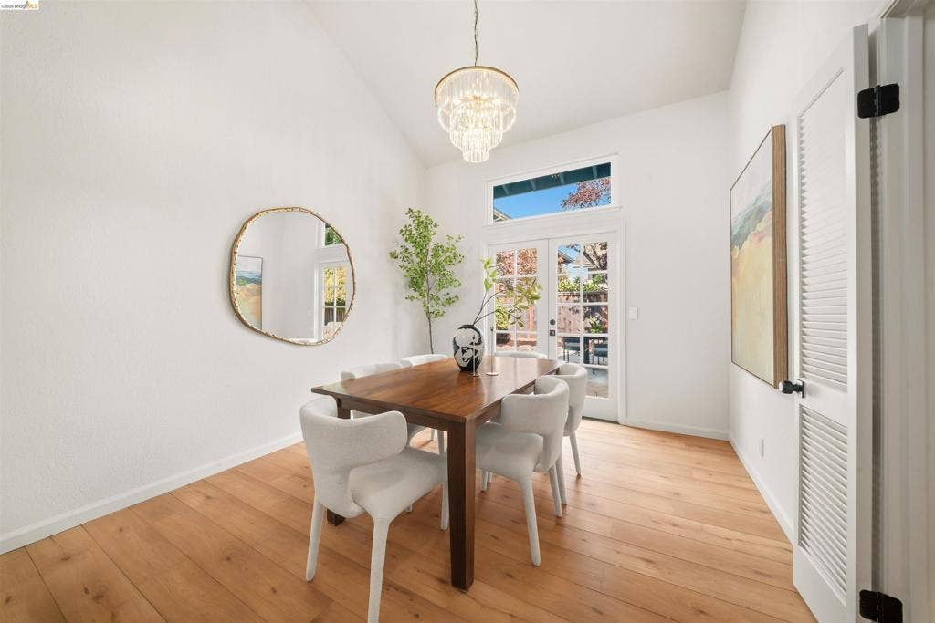 Vaulted ceiling, wood-finish flooring, glass-paned double doors, transom window, and a tiered crystal chandelier