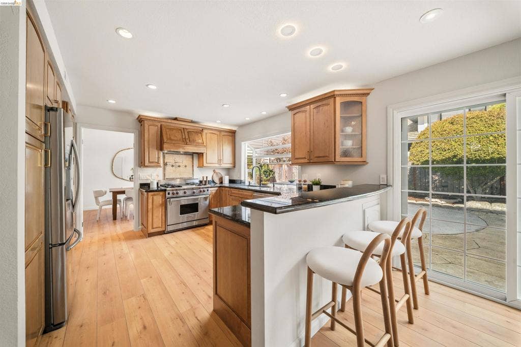 Kitchen featuring wood cabinetry, stainless steel range, recessed lighting, and wood-finish flooring