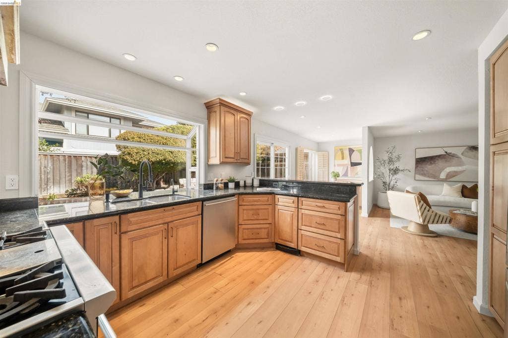 Kitchen with wood-finish flooring, recessed lighting, and a large pass-through window